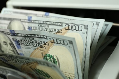 Photo of Money counter machine with dollar banknotes, closeup