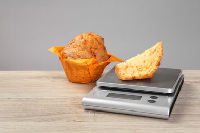 Photo of Kitchen scale with piece of muffin on light wooden table. Space for text