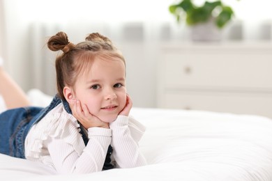 Photo of Portrait of cute little girl on bed indoors, space for text