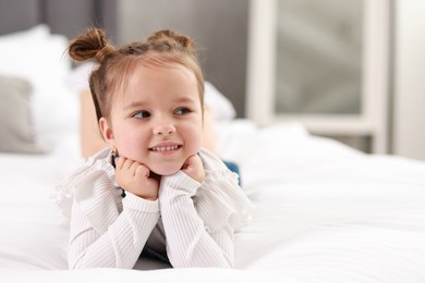 Photo of Portrait of happy little girl on bed indoors, space for text