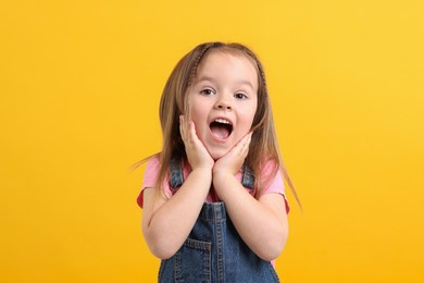 Photo of Portrait of emotional little girl on orange background