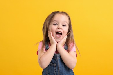 Portrait of emotional little girl on orange background