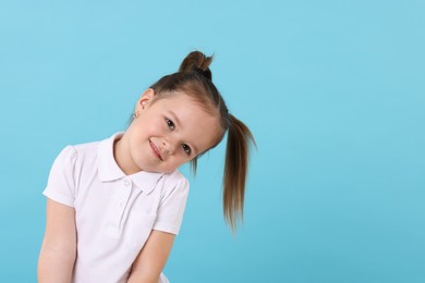 Photo of Portrait of cute little girl on light blue background, space for text