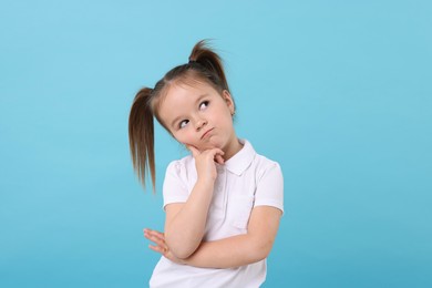 Photo of Portrait of cute little girl on light blue background