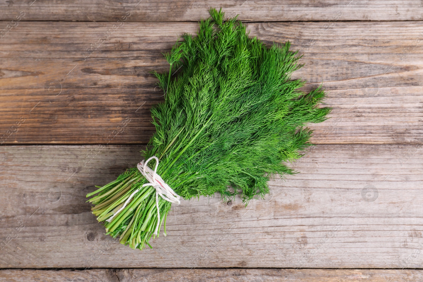 Photo of Bunch of fresh green dill on wooden table, top view