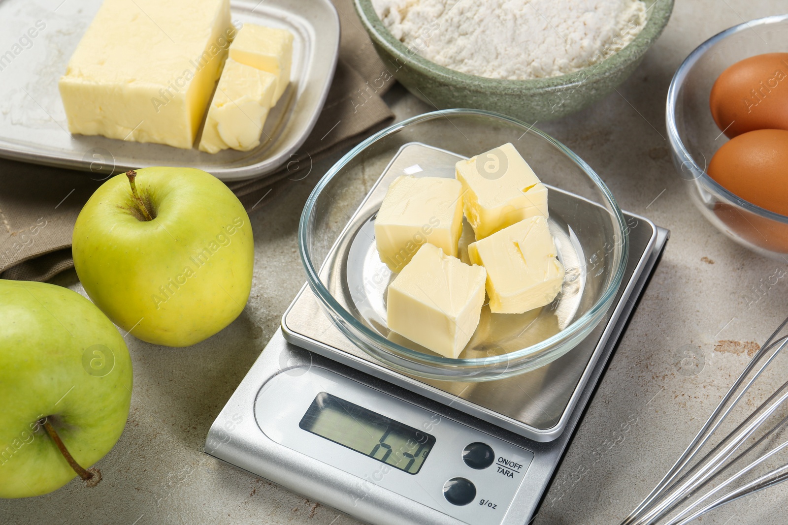 Photo of Kitchen scale with bowl of butter and other products on grey table