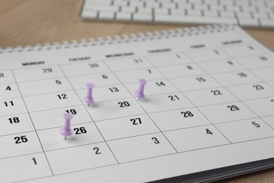 Photo of Timetable. Calendar page and drawing pins on table, closeup