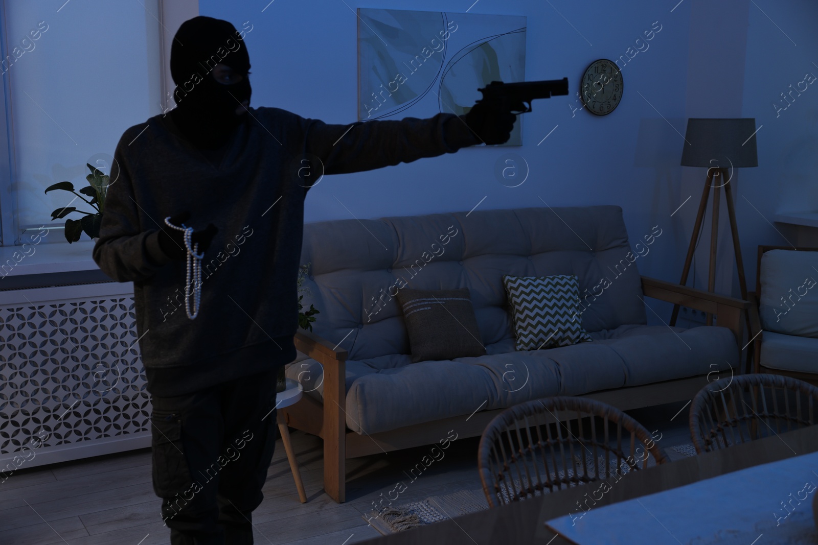 Photo of Thief with gun stealing jewels in foreign house. Burglary