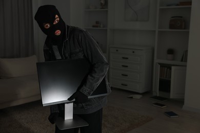 Thief stealing computer monitor at foreign house. Burglary