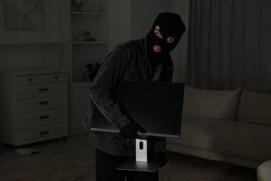 Thief stealing computer monitor at foreign house. Burglary