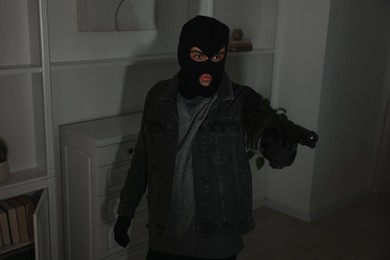 Photo of Thief with gun at foreign house. Burglary