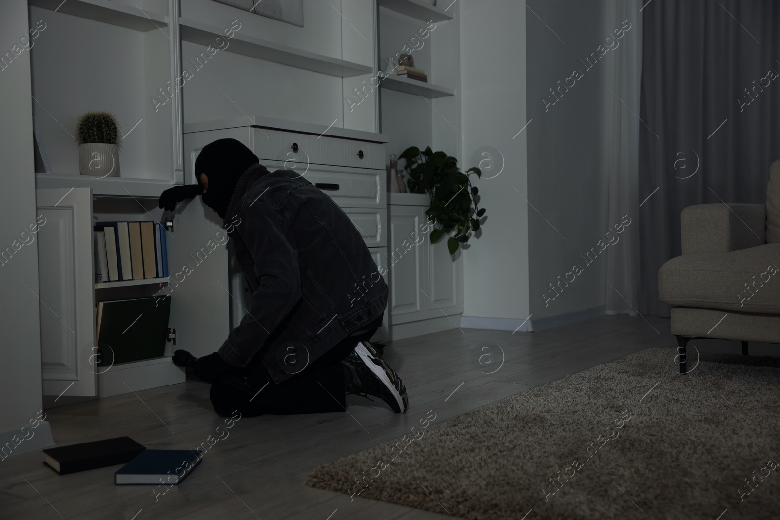 Photo of Thief looking for money in chest of drawers at foreign house. Burglary