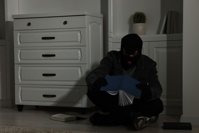 Photo of Thief looking for money near chest of drawers at foreign house. Burglary