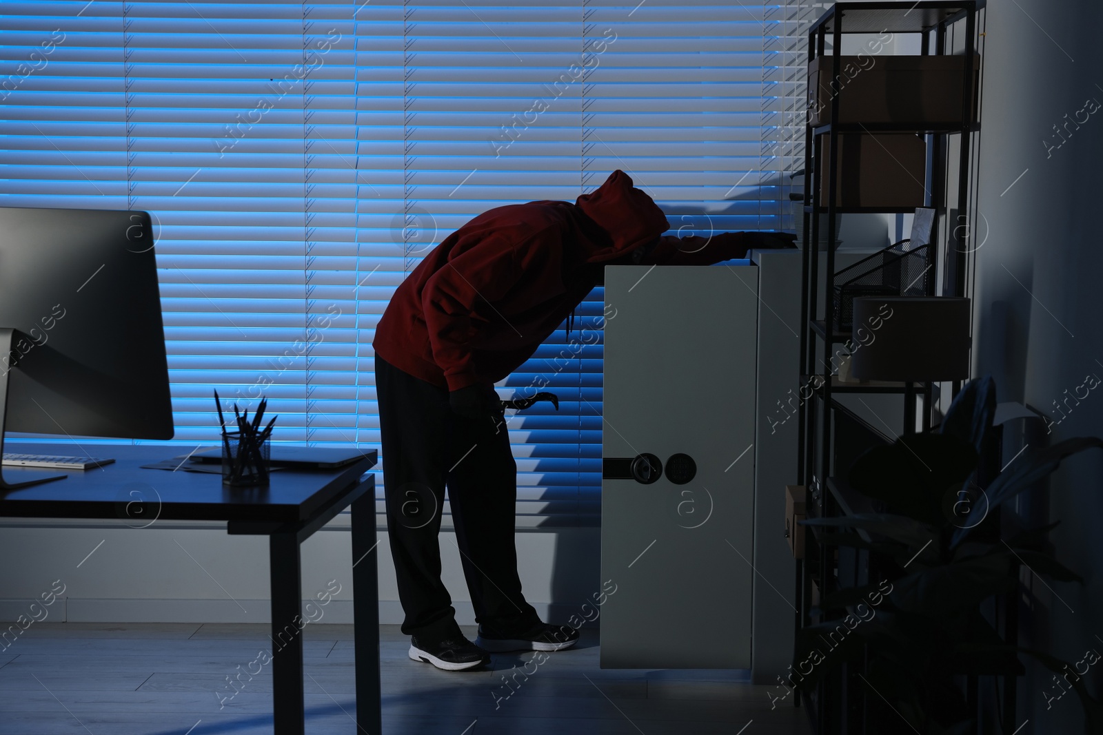 Photo of Thief looking for money in office at night. Burglary