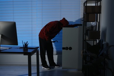 Photo of Thief looking for money in office at night. Burglary