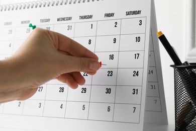 Photo of Timetable. Man marking date in calendar with drawing pins, closeup