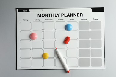 Photo of Timetable. Planner with bright magnets and red felt pen on grey table, top view