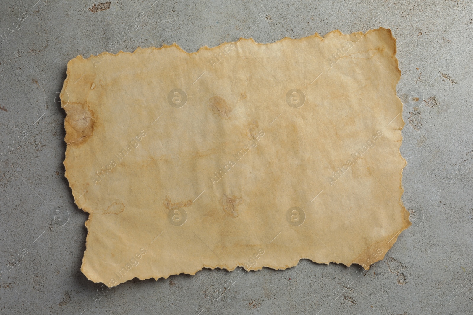 Photo of Sheet of old parchment paper on grey table, top view