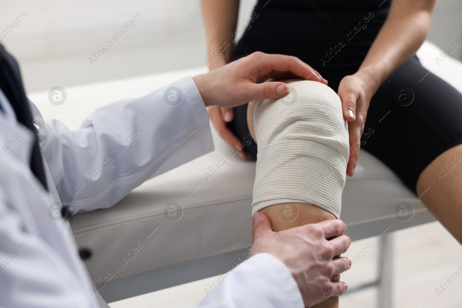 Photo of Sports injury. Doctor examining patient's knee in hospital, closeup