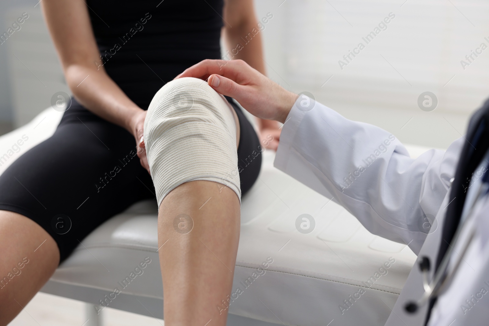 Photo of Sports injury. Doctor examining patient's knee in hospital, closeup