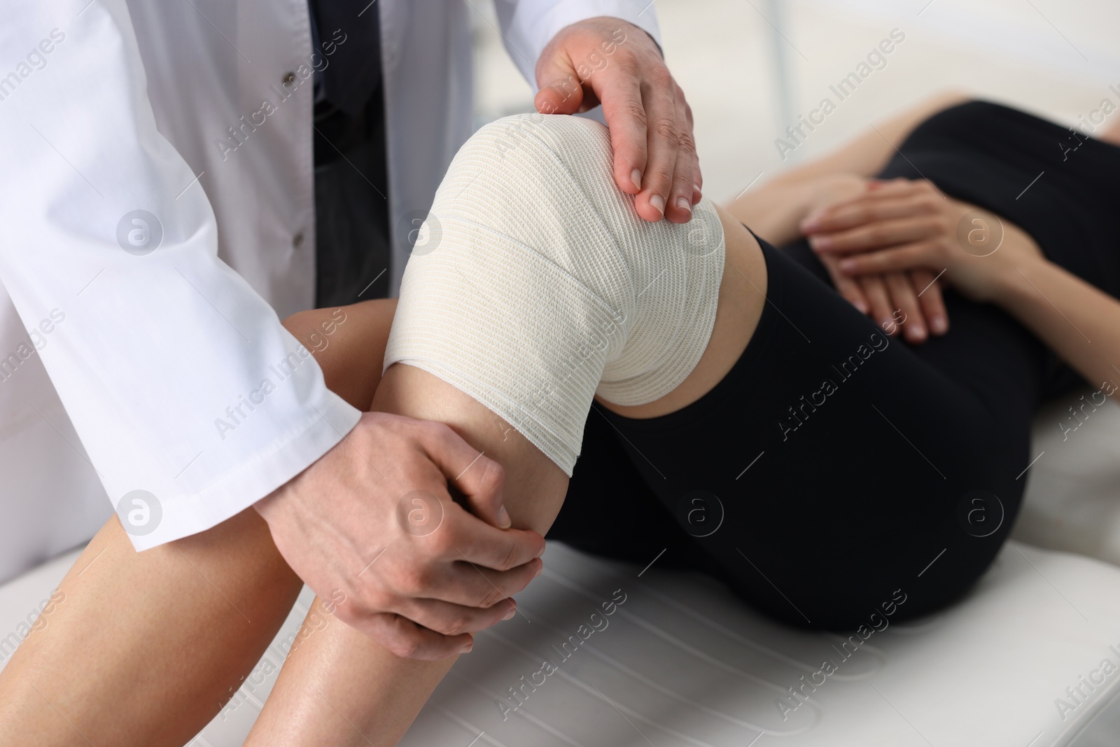 Photo of Sports injury. Doctor examining patient's knee in hospital, closeup