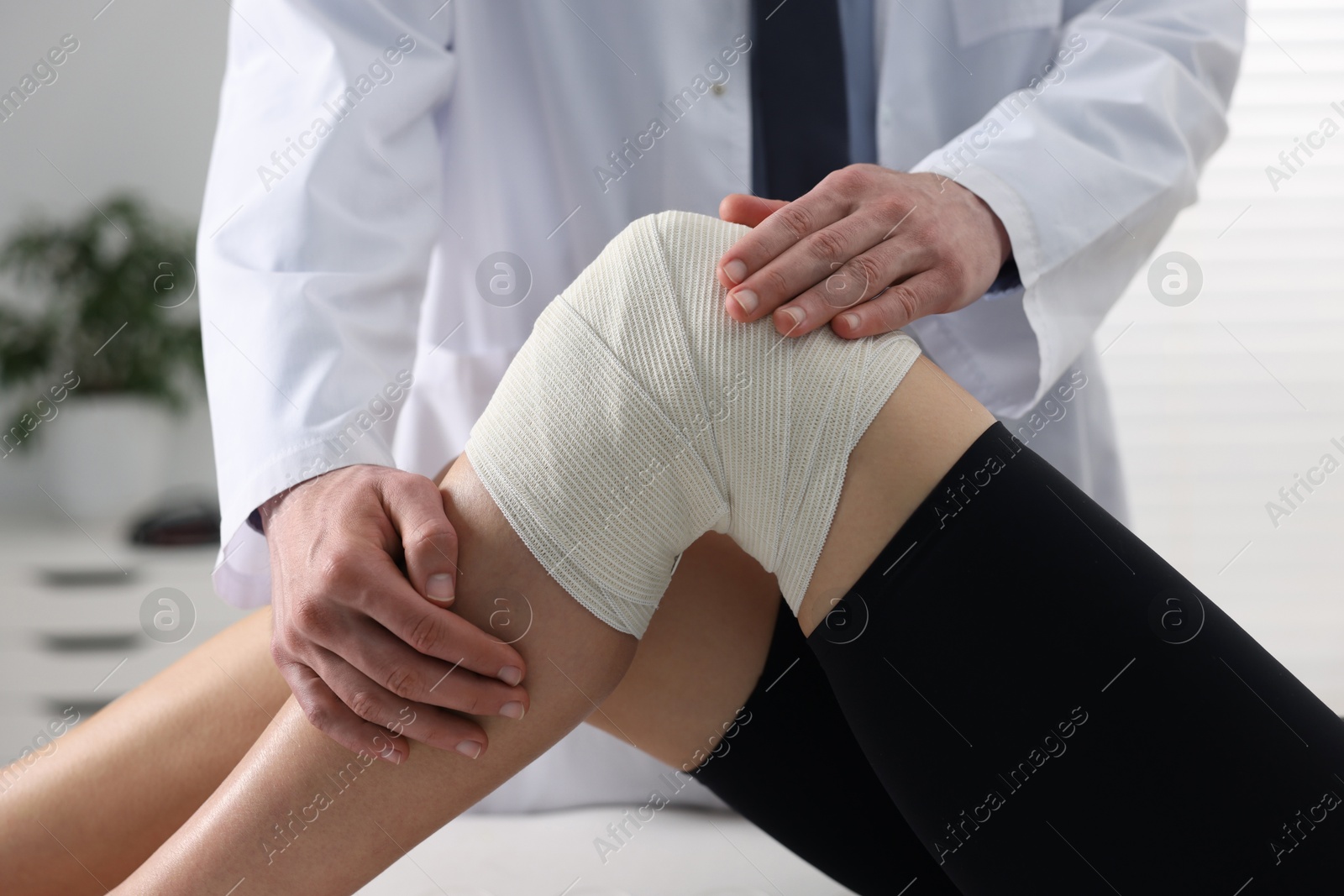 Photo of Sports injury. Doctor examining patient's knee in hospital, closeup