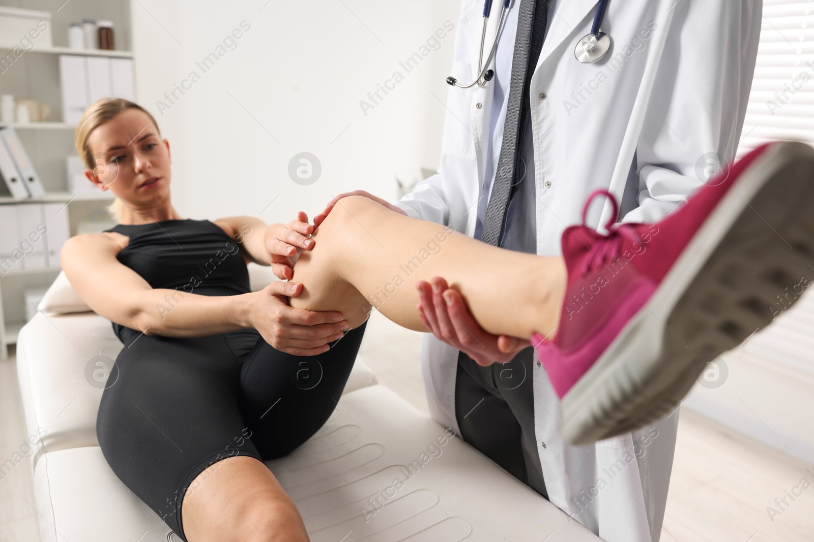 Photo of Sports injury. Doctor examining patient's leg in hospital, closeup