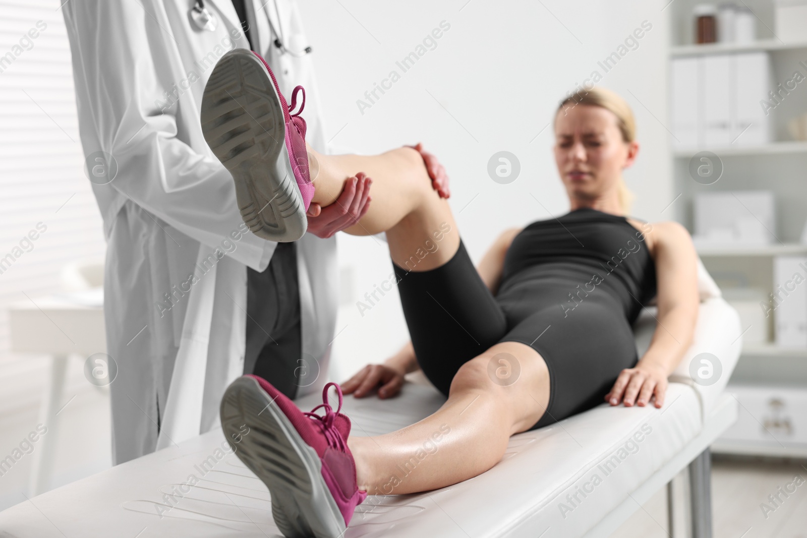 Photo of Sports injury. Doctor examining patient's leg in hospital, closeup