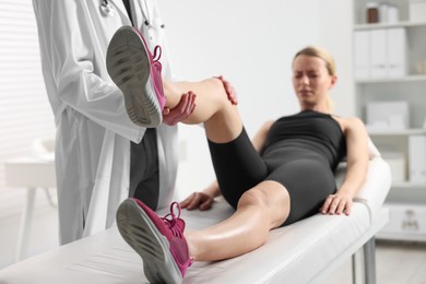 Photo of Sports injury. Doctor examining patient's leg in hospital, closeup