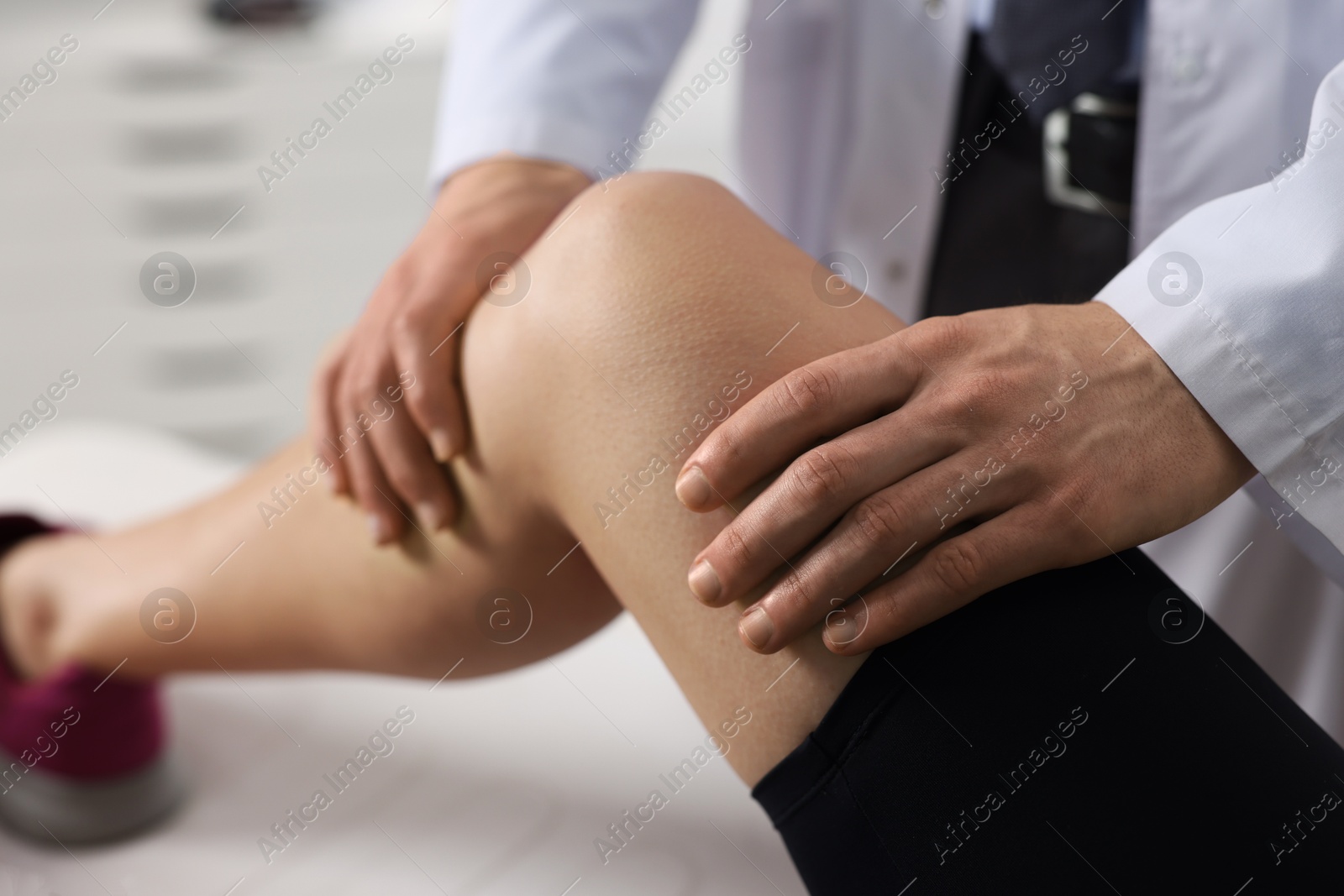 Photo of Sports injury. Doctor examining patient's leg in hospital, closeup