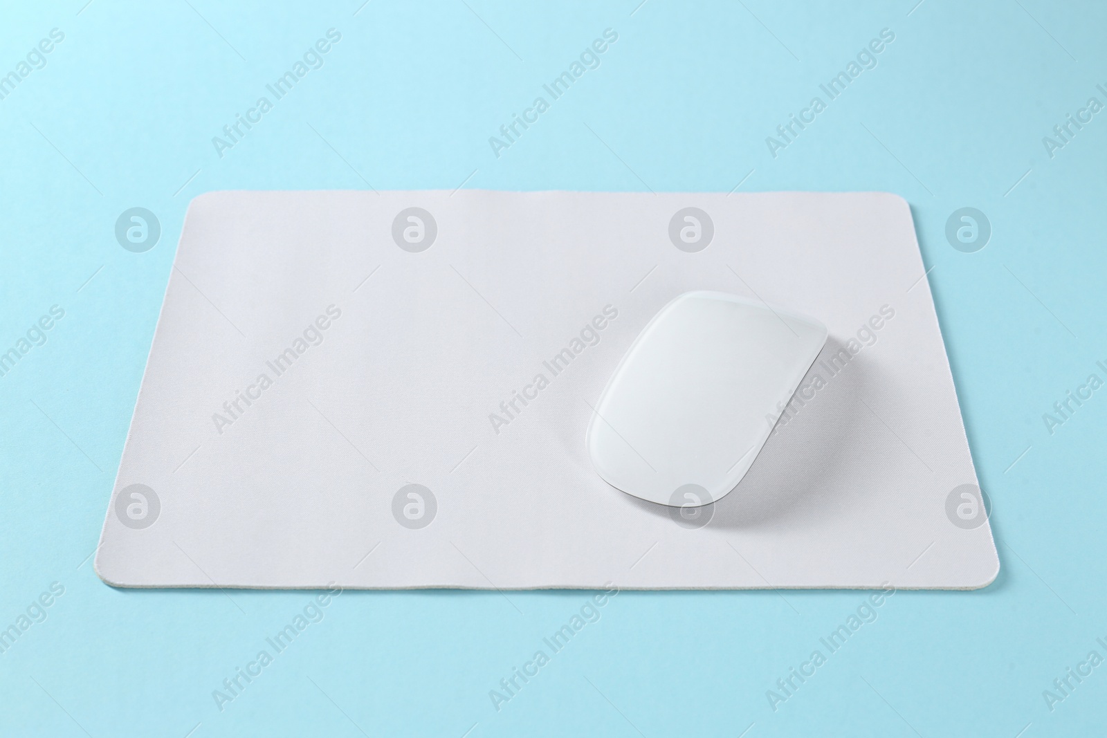 Photo of Wireless mouse and mousepad on light blue background