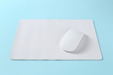 Photo of Wireless mouse and mousepad on light blue background