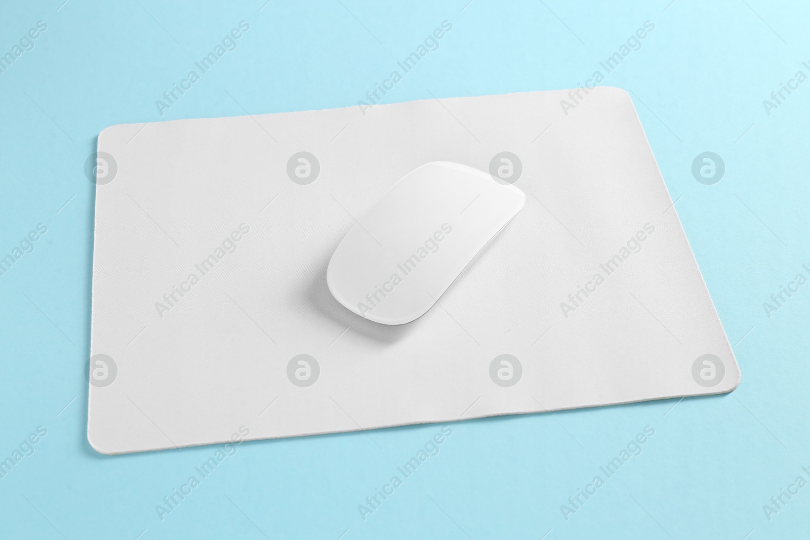 Photo of Wireless mouse and mousepad on light blue background