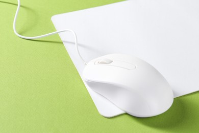 Wired mouse and mousepad on green background, space for text