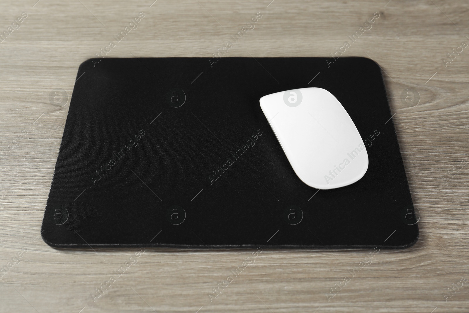 Photo of Wireless mouse and mousepad on wooden table