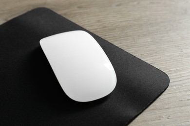 Wireless mouse and mousepad on wooden table, closeup