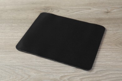 One black mouse pad on wooden table