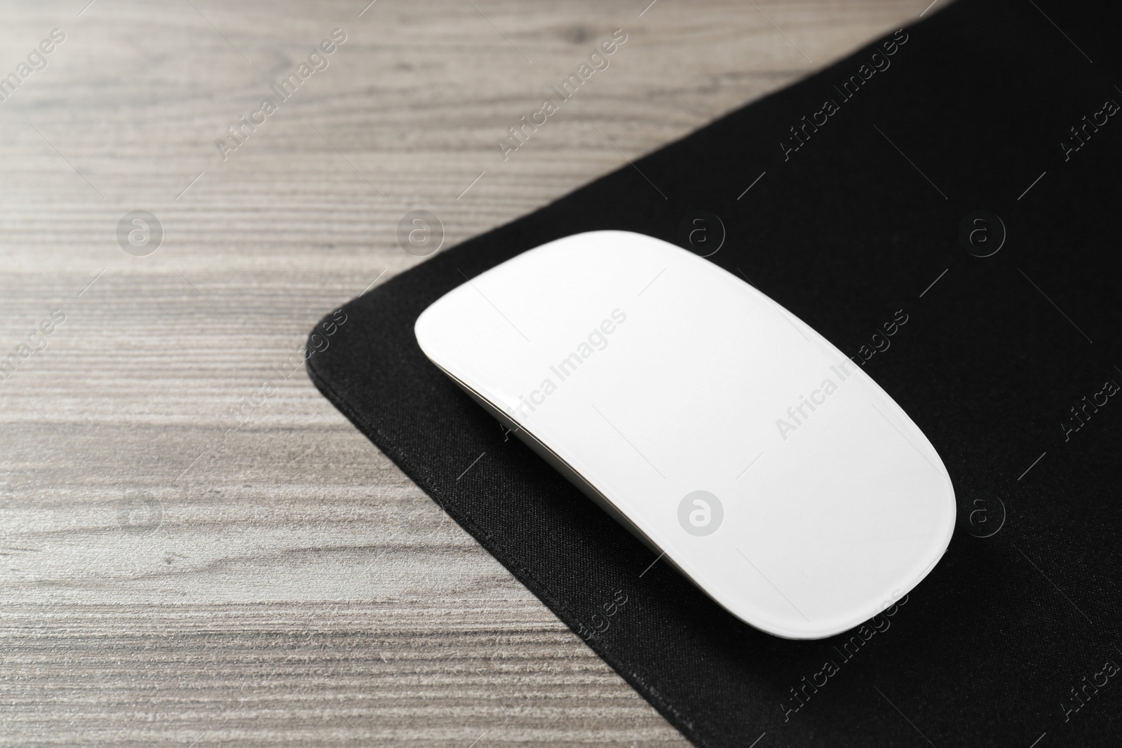 Photo of Wireless mouse and mousepad on wooden table, closeup. Space for text