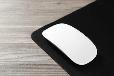 Wireless mouse and mousepad on wooden table, closeup. Space for text