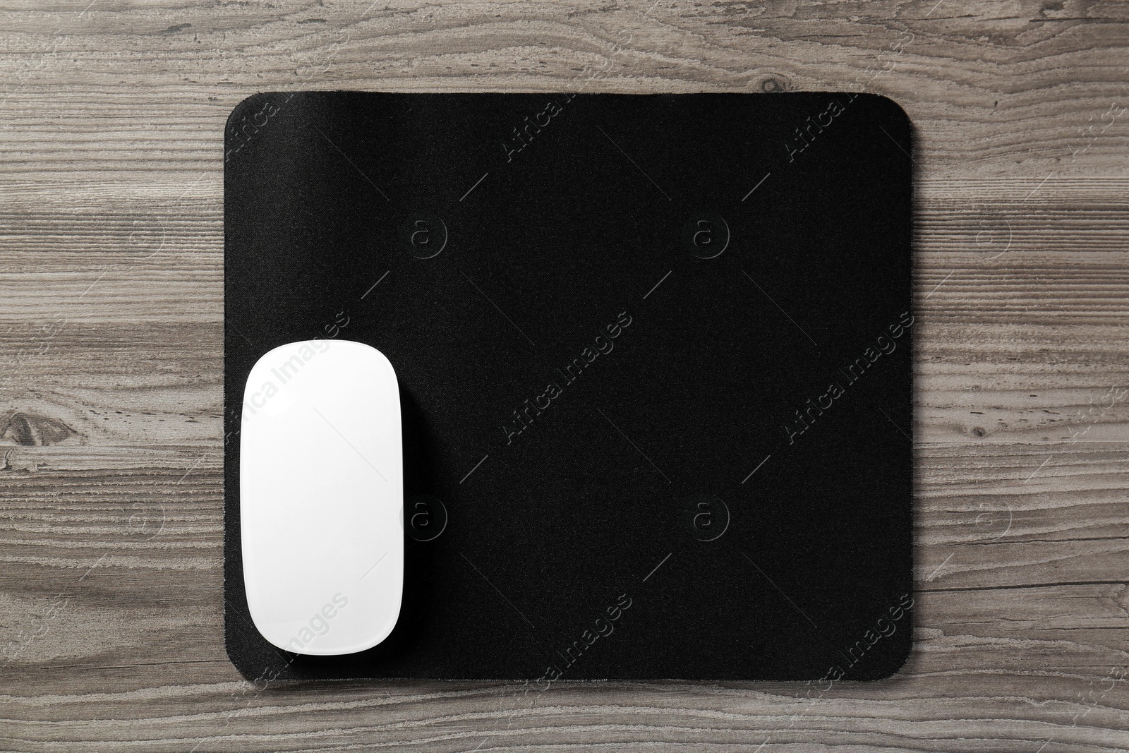 Photo of Wireless mouse and mousepad on wooden table, top view