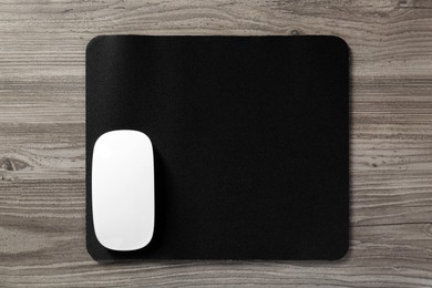 Wireless mouse and mousepad on wooden table, top view