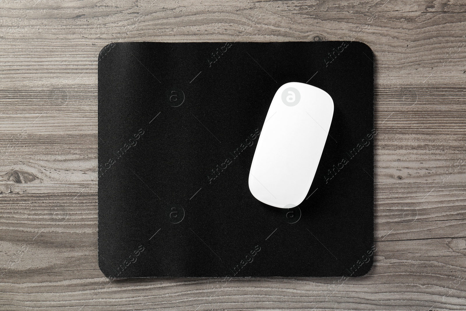 Photo of Wireless mouse and mousepad on wooden table, top view