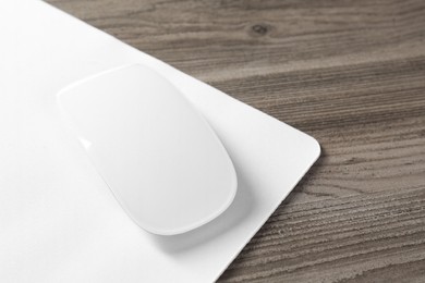 Photo of Wireless mouse and mousepad on wooden table, closeup