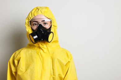 Photo of Worker in respirator, protective suit and glasses on grey background, space for text