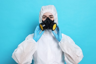 Photo of Worker in respirator and protective suit on light blue background