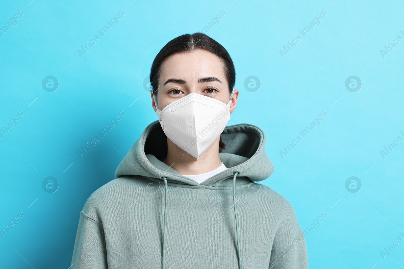 Photo of Woman in respirator mask on light blue background