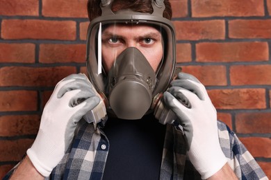 Photo of Man in respirator mask near red brick wall