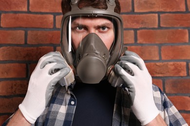 Man in respirator mask near red brick wall