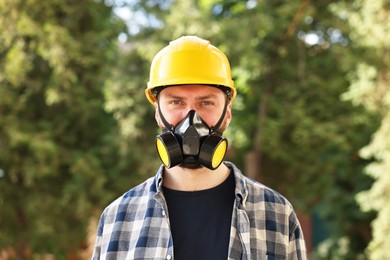 Man in respirator mask and hard hat outdoors. Safety equipment