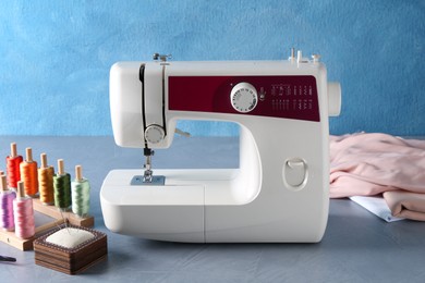 Photo of White sewing machine and craft accessories on gray table near light blue wall